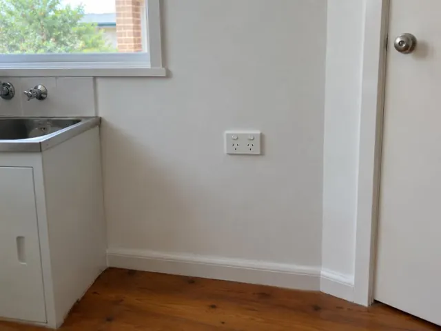 White double power point on a painted kitchen wall beside a sink and door in Collaroy